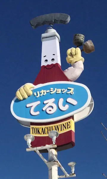 ワインボトルを模した照井商店の看板。赤と白のデザインで「十勝ワイン」と記載されている